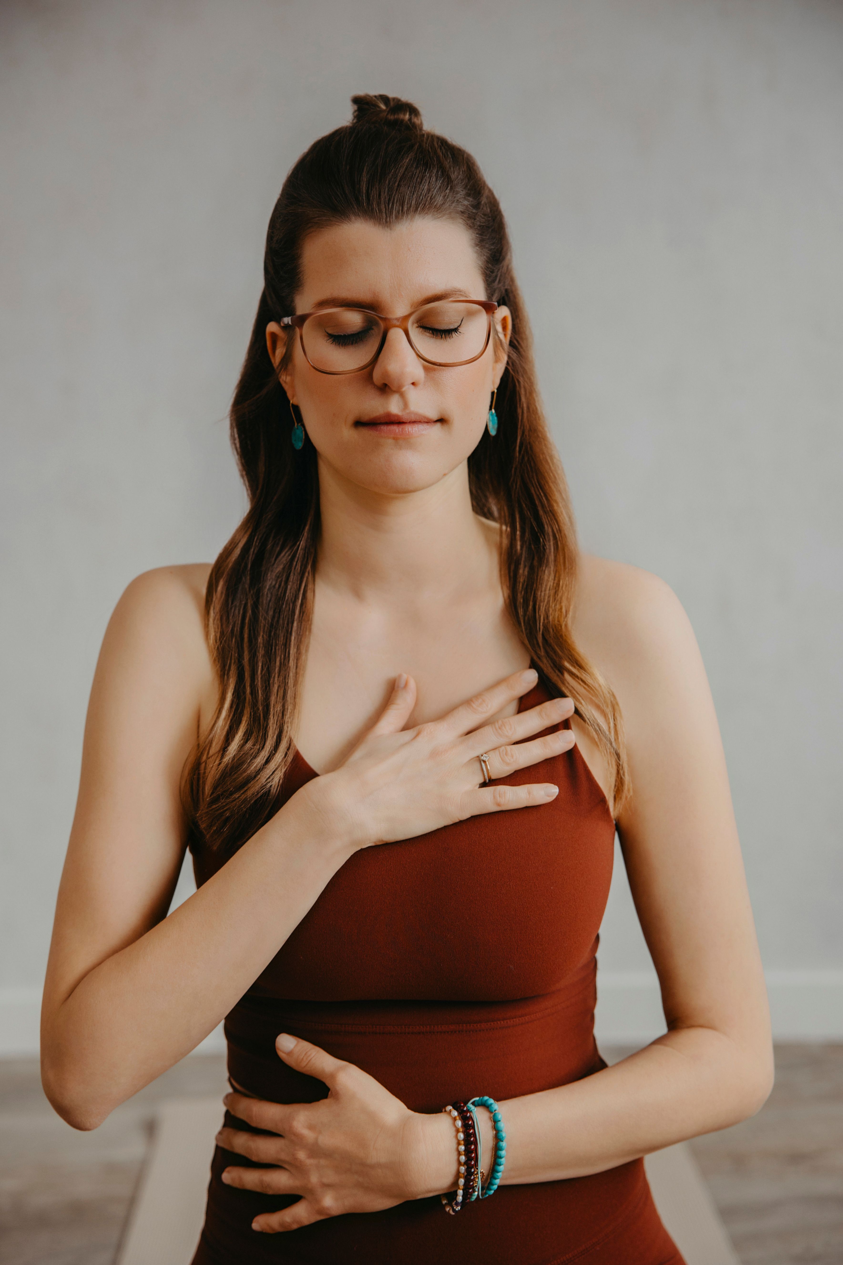 Sharon hat die Augen geschlossen und hat ihre Hände auf Herz und Bauch gelegt. Blick und Aufmerksamkeit sind ins Innere gerichtet.