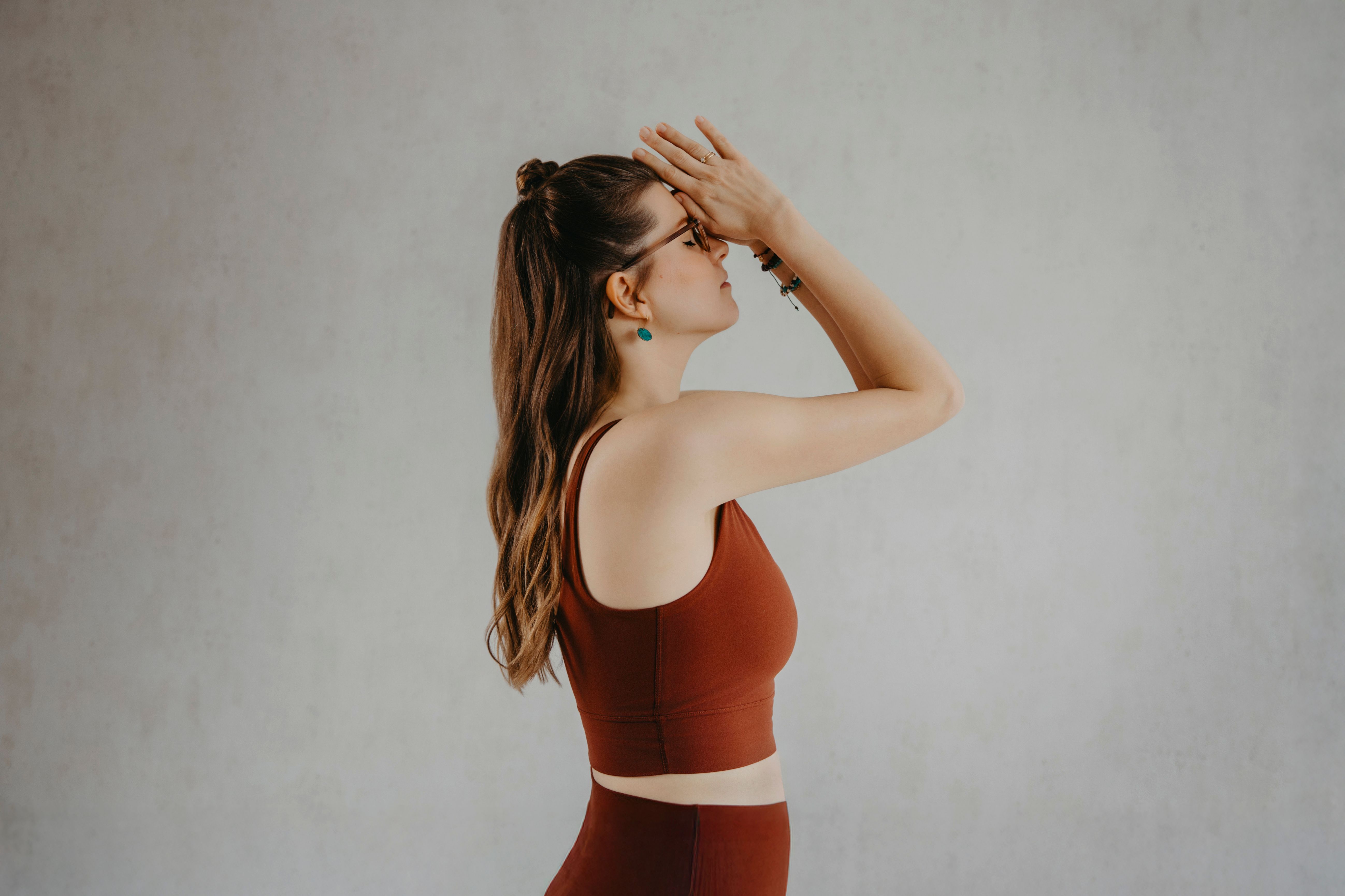 Yoga-Lehrerin Sharon mit geschlossenen Augen in Namaste-Geste, Daumen am Dritten Auge an der Stirn – Geste der Dankbarkeit und Achtsamkeit